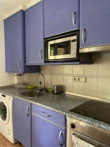 a kitchen with purple cabinets and a microwave at Rio Deba Gardens in San Sebastián