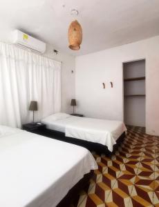 2 Betten in einem Zimmer mit weißen Wänden in der Unterkunft Casa el Muelle in Coveñas