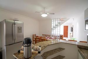 a kitchen with a stainless steel refrigerator and a dining room at DUPLEX 2 SUÍTES CONDOMÍNIO MONT CARMELO in Porto Seguro