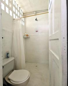 y baño blanco con aseo y ducha. en Casa el Muelle en Coveñas
