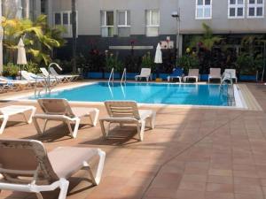 a pool with chaise lounge chairs and a hotel at PLAYA DEL NORTE VIVIENDA VACACIONAL in Gáldar