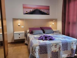 a bedroom with a bed with a purple stuffed animal on it at PLAYA DEL NORTE VIVIENDA VACACIONAL in Gáldar