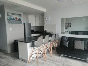 a kitchen with a counter and chairs in a room at DURBAN BEACHFRONT Tenbury 903 in Durban