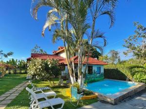 una casa con una piscina y una palmera en Villa Los Caciques By Hospedify - Hermosa Villa con Piscina, Billar, Zona de BBQ y Domino, en Jarabacoa