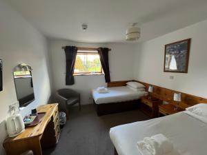 a hotel room with two beds and a desk at Smithton Hotel in Inverness