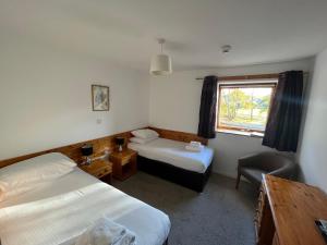 Habitación con 2 camas, silla y ventana en Smithton Hotel, en Inverness