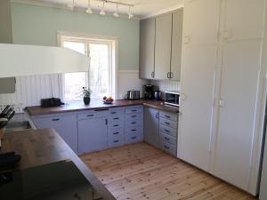 a kitchen with white cabinets and a wooden floor at Gula huset, Lakene Ostgård in Lakene