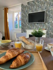 Le Carrousel - Appartement cosy centre Obernai في أوبرناي: طاولة مع رغيفين من الخبز وكأسين من عصير البرتقال