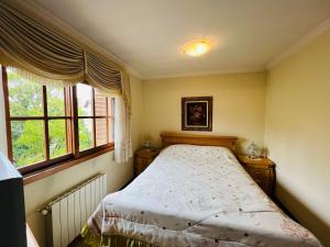 1 dormitorio con 1 cama y 2 ventanas en MRG- Colonial 2D - 200 mts da Rua Torta, en Gramado