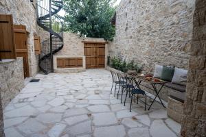 a patio with a table and chairs and a stone wall at Palazzino Luxury Suites in Lofou
