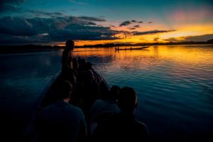 a group of people on a boat in the water at sunset at Jamu Lodge in the Cuyabeno Wildlife Reserve in Cuyavenus