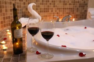 Dois copos de vinho tinto ao lado de uma banheira. em Hotel Santorian em Hermosillo