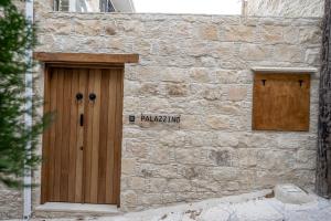 Edificio de piedra con puerta de madera y 2 ventanas en Palazzino Luxury Suites, en Lofou