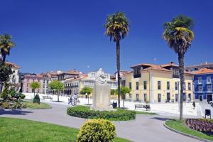 a street with palm trees and a statue in a town at Antiguo Casino Hotel in Pravia