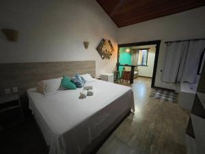 a bedroom with a large white bed with two teddy bears on it at Pousada Cipó Prata in Serra do Cipo