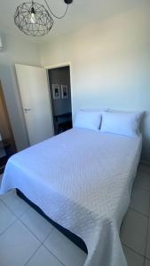 una camera da letto con un grande letto bianco con lenzuola bianche di Apartamento Frente ao Mar Santos II a Santos