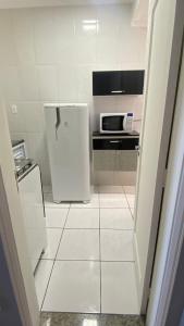 a white kitchen with a refrigerator and a microwave at Apartamento Frente ao Mar Santos II in Santos
