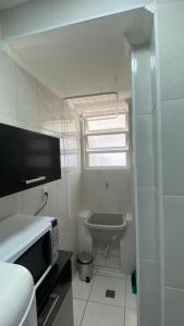 a small white bathroom with a sink and a microwave at Apartamento Frente ao Mar Santos II in Santos