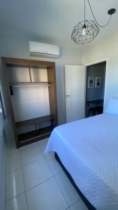 Apartamento Frente ao Mar Santos II في سانتوس: غرفة نوم بسرير ابيض وخزانة