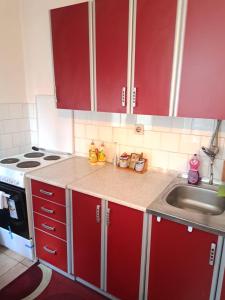 a kitchen with red cabinets and a sink at Stan na dan Novi Grad in Bosanski Novi +15 photos