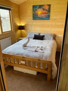een slaapkamer met een bed in een blokhut bij Cosy 2 BR cabin on coast private hot tub ' Driftwood ' in Stolford