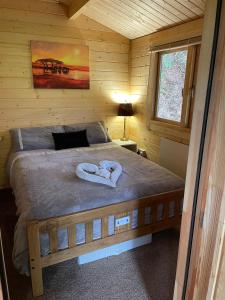 a bedroom with a bed with two towels on it at Cosy 2 BR cabin on coast private hot tub ' Driftwood ' in Stolford