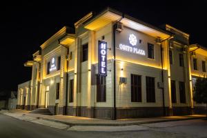 Un edificio con un cartel delante por la noche. en Osiyo Plaza Hotel, en Samarkand