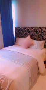 a large white bed with a pink pillow on it at Bedfort Accommodation in Cape Town