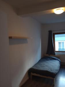 een kleine slaapkamer met een bed en een raam bij Studio régence in Luik