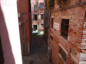Un callejón en un viejo edificio con un cartel. en Casa Forner, Venezia, en Venecia