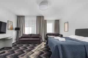 Aparthotel Etna في كولوبرزيغ: غرفة فندق بسرير واريكة وتلفزيون