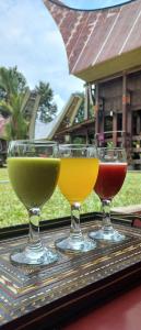 tres copas de vino sentadas sobre una mesa en Toraja Homestay & Coffee Bunna, en Rantepao
