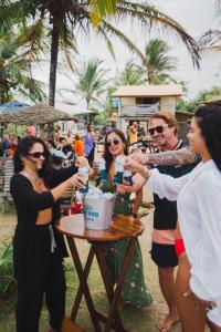 un grupo de personas de pie alrededor de una mesa con bebidas en Caramuru Hostel Caraíva en Caraíva