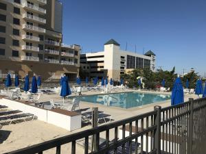 a swimming pool with chairs and blue umbrellas at 14 Clipper on the Bay in Ocean Pines