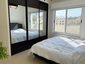 a bedroom with two beds and a large window at 360 Rooftop Apartment in Dabouq in Amman