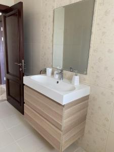 La salle de bains est pourvue d'un lavabo blanc et d'un miroir. dans l'établissement 360 Rooftop Apartment in Dabouq, à Amman