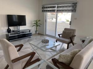 sala de estar con TV, 2 sillas y mesa de cristal en 360 Rooftop Apartment in Dabouq, en Amán