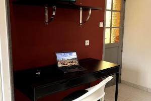 un ordenador portátil sentado en la parte superior de un escritorio negro en Studio avec accès indépendant: Le 15 Bis, en Violaines