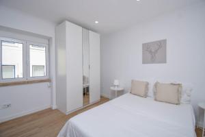 ein weißes Schlafzimmer mit einem Bett und einem Fenster in der Unterkunft Laranjal 7 in Lissabon