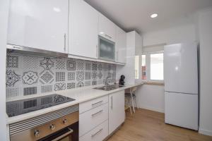 eine weiße Küche mit einer Spüle und einem Kühlschrank in der Unterkunft Laranjal 7 in Lissabon