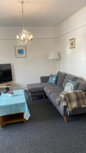 uma sala de estar com um sofá e um lustre em Bexhill Luxury Sea Stay Flat 2 em Bexhill