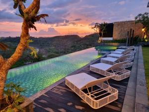 a pool with lounge chairs on a deck with a sunset at Truntum Boutique Mandalika in Kuta Lombok