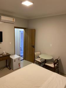 um quarto com uma cama, uma mesa e cadeiras em Pousada Villa Guimaraes em Chapada dos Guimarães