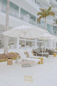 a patio with two white umbrellas and chairs and a building at Máritima Golf New apartment private beach access in Nuevo Vallarta