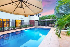 una piscina con sombrilla y una casa en Parap Estate Pool Paradise from the Top-floor en Parap