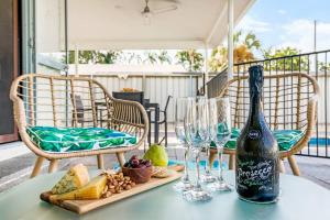 - une bouteille de vin assise sur une table avec des verres à vin dans l'établissement Cool by the Pool - A Private Beachside Retreat, à Fannie Bay