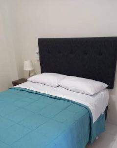 a large bed with a black headboard and white pillows at Loft Central en Lamas in Lamas