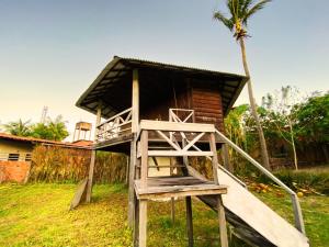 een houten strandwachthuisje met een palmboom bij Chalés da VoVó in Atins