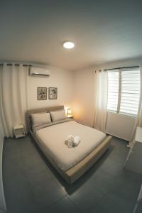 a bedroom with a large bed with white sheets and a window at SOKZO Miramar in San Juan
