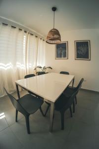 a white dining room table with chairs and a pendant at SOKZO Miramar in San Juan